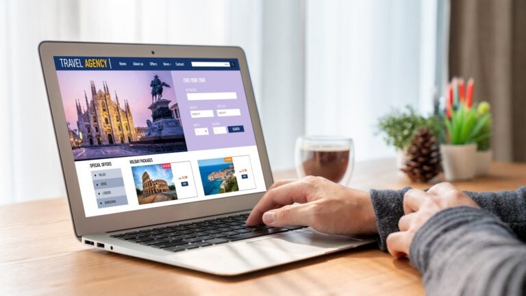 Person browsing a travel booking website on a laptop to search for flights and hotels