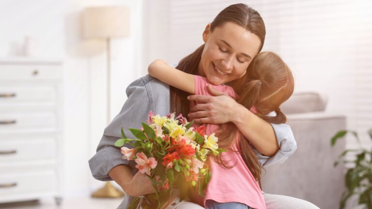 Little girl presenting a bouquet of flowers to her mother indoors on Mother's Day