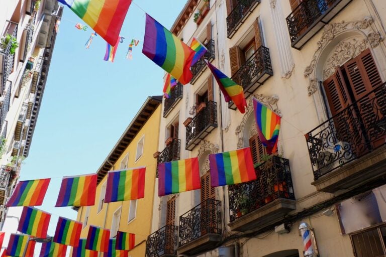 Rainbow flags hanging between classical buildings in Chueca neighborhood.