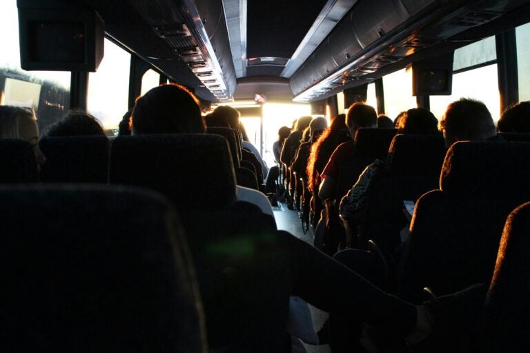 A bus filled with passengers driving through historic streets in Europe.
