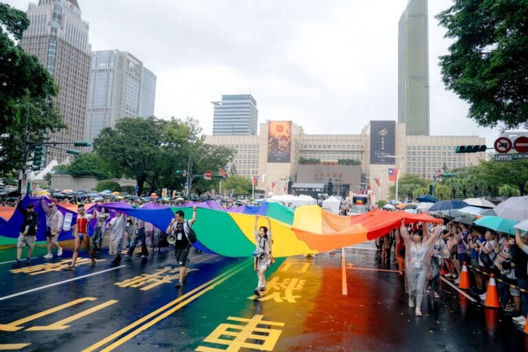 Participants carry a large rainbow flag during a pride parade.
