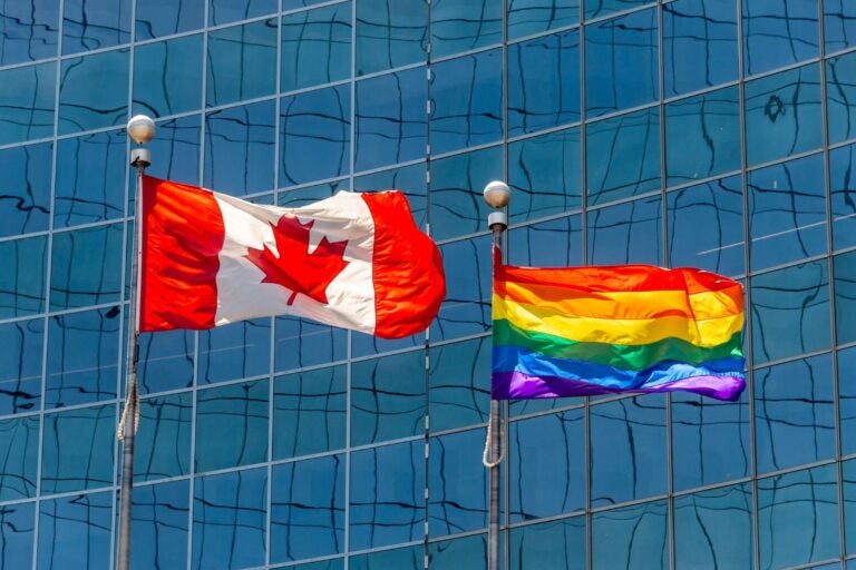 Canadian flag next to rainbow flag in Toronto.