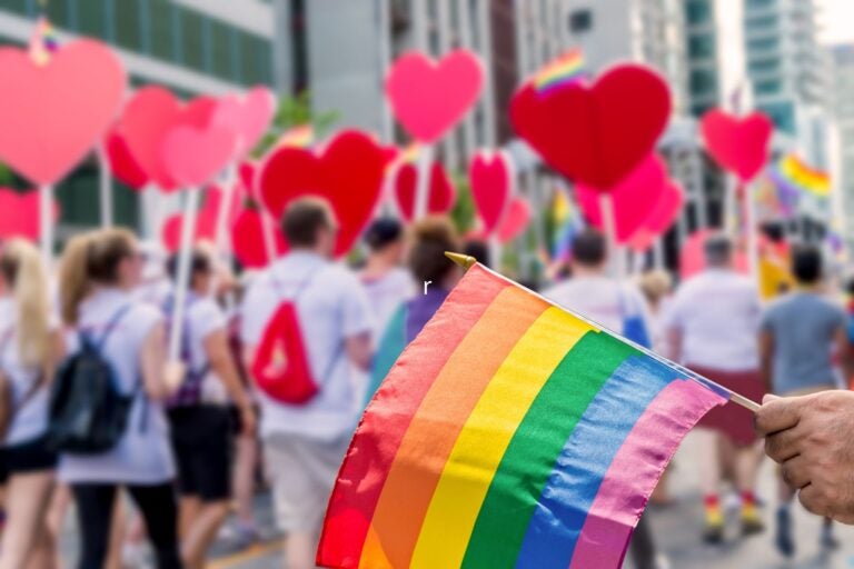 Rainbow flag floating in front of the gay pride participants.