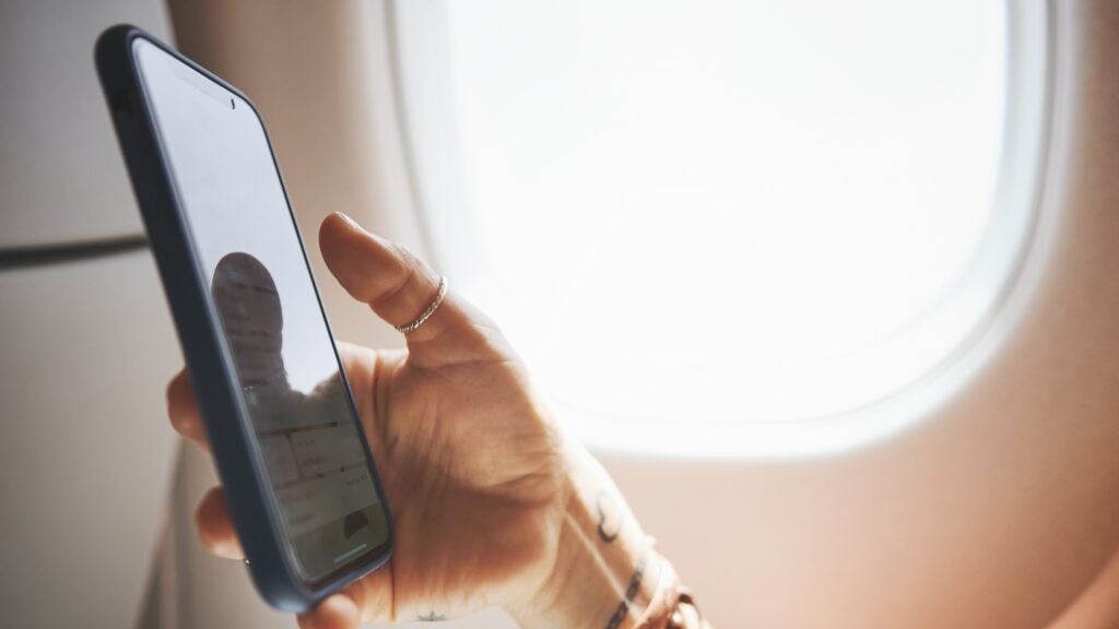  Traveler checking their phone for a digital boarding pass while seated on a plane
