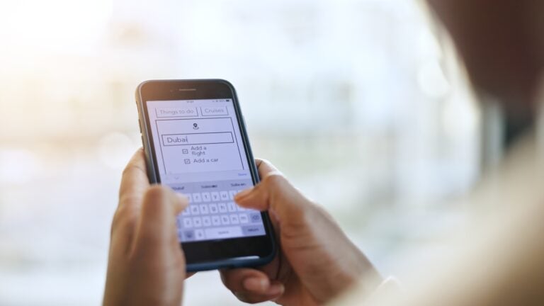 Close-up of a business traveller's hands holding a smartphone, browsing flight information on a travel app.