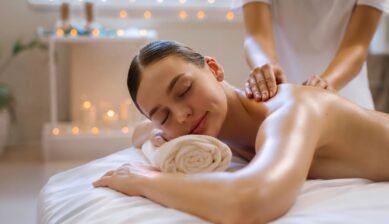 Happy woman lying face down on a massage table at a spa, smiling with eyes closed during a body treatment
