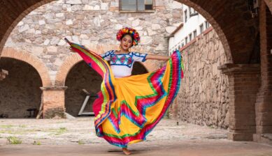 Young woman wearing a colorful traditional folklórico dress at a Cinco de Mayo parade or cultural festival