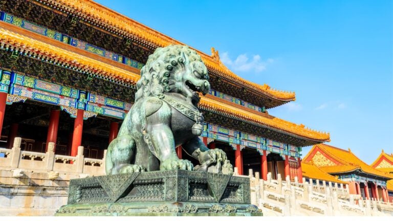 A large ornate bronze lion statue standing guard at the entrance to the Forbidden City in Beijing, China.