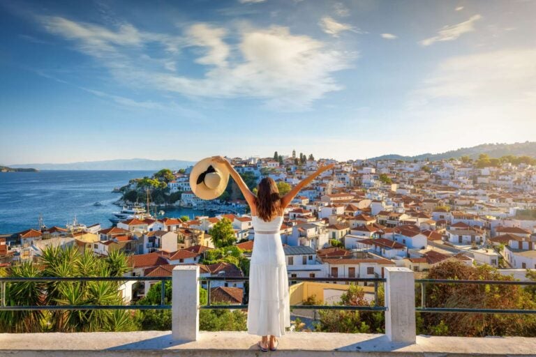 woman standing on top of a street with a greek landscape at the bottom