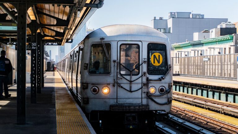 A New York City subway train traveling along an above-ground section of track.