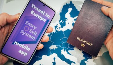 Hands placing a passport and a smartphone showing the Entry/Exit System mobile app on a map of Europe.
