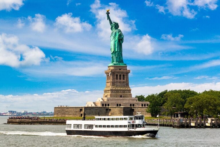 Statue of Liberty and tourist ship ferry in NYC, USA