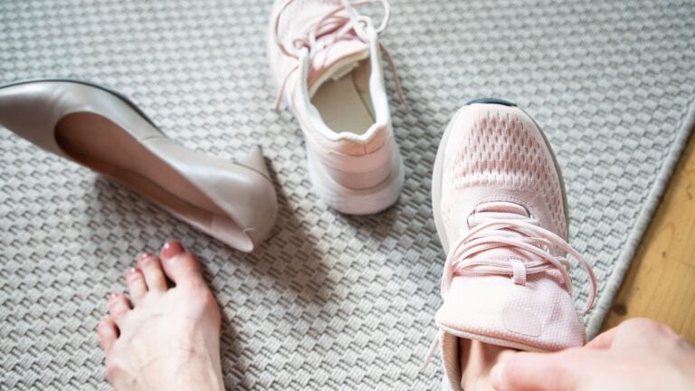 Woman swapping a pair of high heels for athletic sneakers