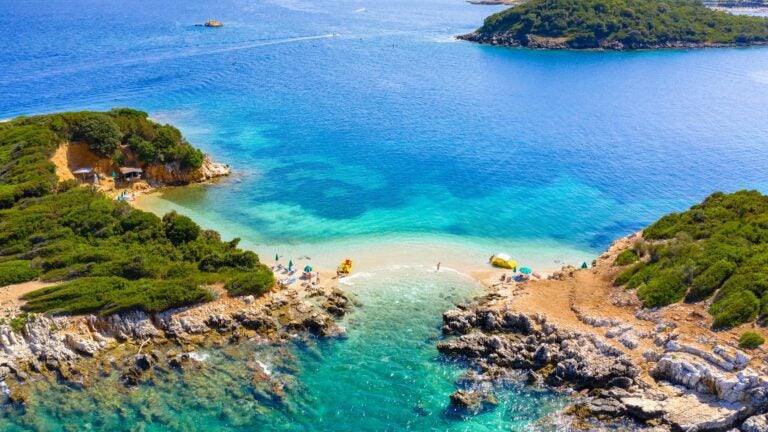 Clear turquoise shallows and small offshore islets at Ksamil beach on the Albanian Riviera