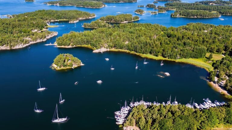 Aerial view of forested islands and islets scattered across the blue water of the Stockholm archipelago