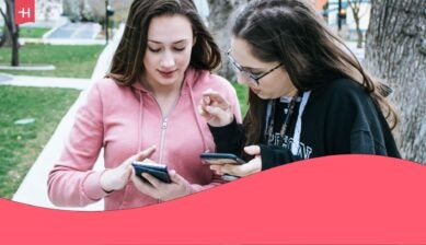 two women talking and using their phones