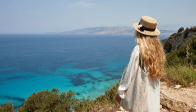Woman in a sun hat gazing out over a bright blue coastal lagoon