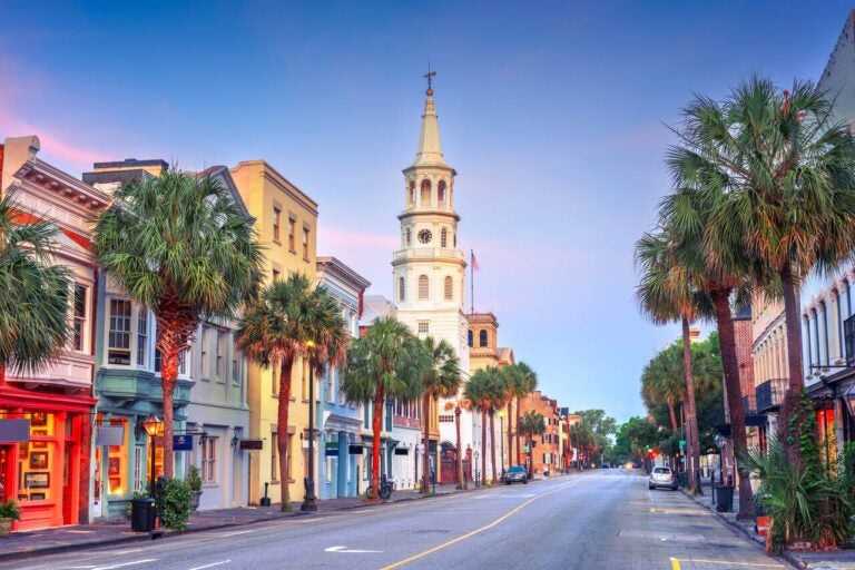 Historic street in Charleston, South Carolina, lined with palm trees and colorful buildings.