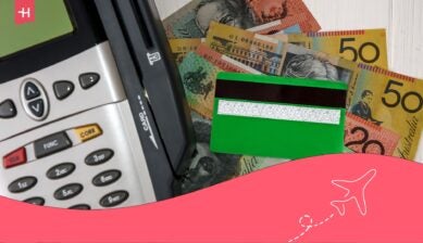 A card payment terminal and bank card resting on Australian dollar banknotes