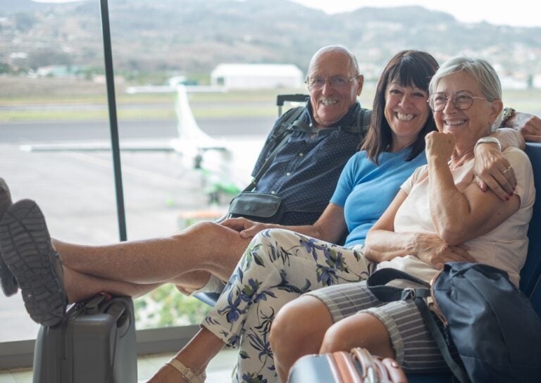 Three retirees sitting at an airport n Arizona waiting for a vehicle to convey them to their homes.