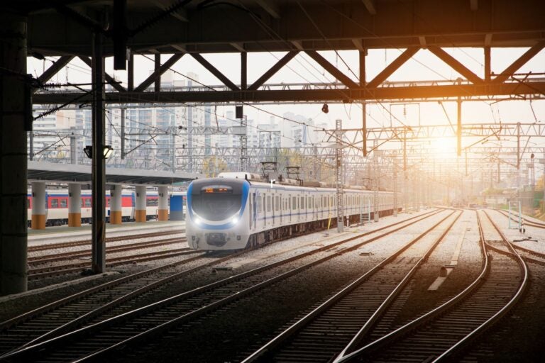 A Busan metro train arriving at a station platform with criss-crossing tracks.