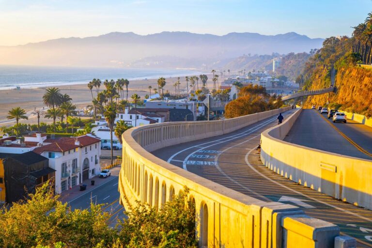 The light of the setting sun stretches over the Santa Monica coastline and the Pacific Coast Highway, as seen from downtown Santa Monica, California