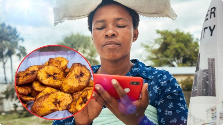 Nigerian street food vendor holding a smartphone, with a close-up of fried plantains displayed beside her.