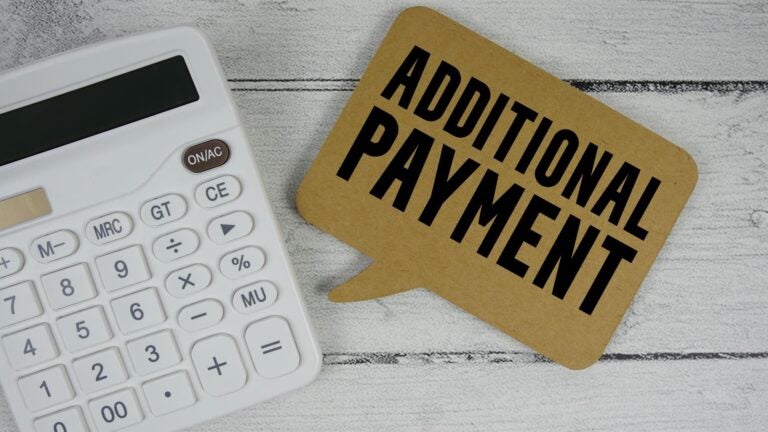 Calculator resting on a wooden surface next to the printed words "Additional Payment."