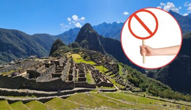Panoramic view of Machu Picchu ruins under a blue sky, with a hand holding a red prohibition sign in a circular inset