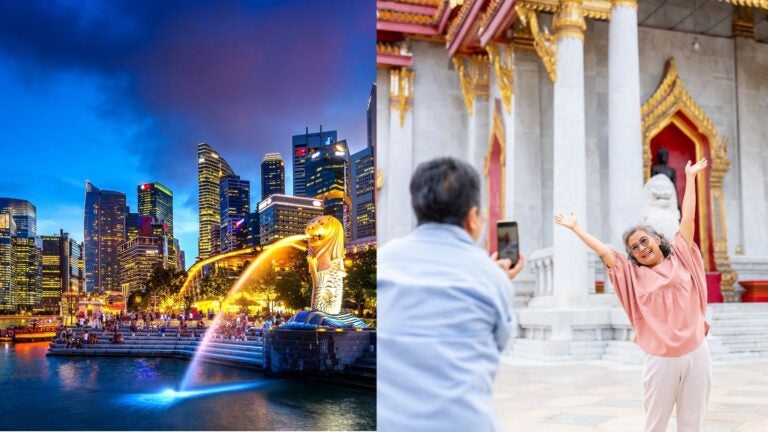 Singapore’s Merlion at night beside an older couple taking photos at a temple.