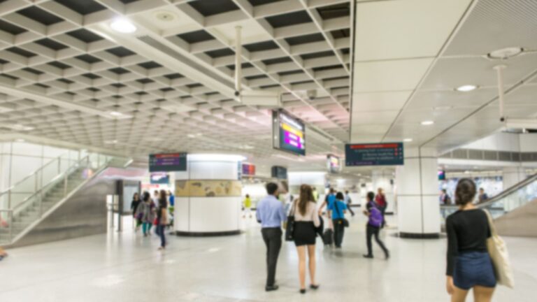 Motion-blurred view of commuters moving through a busy Singapore MRT subway station