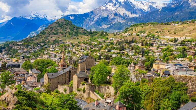 Aerial panorama of the city of Sion in the valley below, framed by the surrounding Swiss Alps in Canton Valais