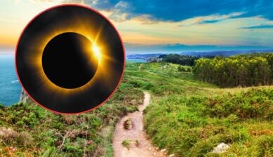 Total solar eclipse with visible corona and diamond ring effect inset in a red circle over a green coastal clifftop trail in northern Spain at dusk