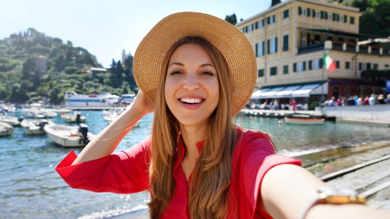 A young woman takes a selfie at a scenic Italian coastal destination.