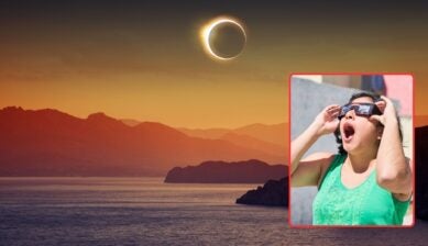 Total solar eclipse forming a diamond-ring effect over a coastal seascape at sunset, with an inset of a woman in a green top wearing eclipse glasses and looking up in awe