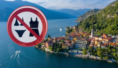 Aerial view of Varenna's colorful lakeside village on Lake Como, overlaid with a red "no swimwear" prohibition sign showing crossed-out bikini and swimsuit icons.