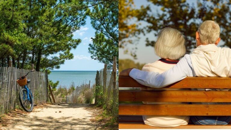 Coastal path with a bicycle beside an older couple relaxing on a bench.
