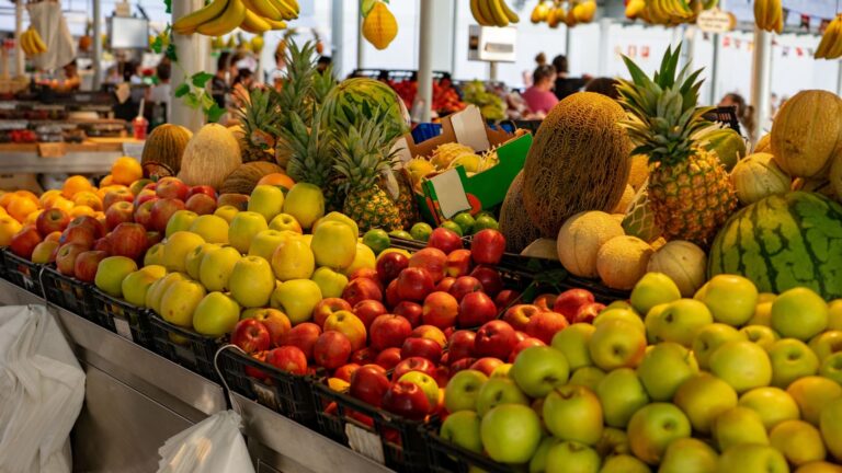 Colorful stalls of fresh fruit, including apples and oranges, on display at Bolhão Market in Porto.