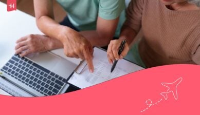 Two people reviewing financial documents related to Social Security benefits, with one pointing to a form while the other takes notes beside a laptop.