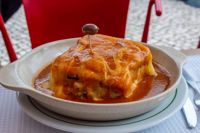 francesinha served with a traditional red suace and olives