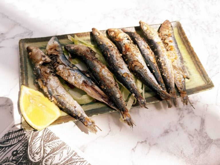 sardinhas assadas served with some lemon next to them