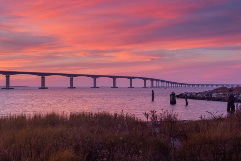 The Marc Basnight Bridge over Oregon Inlet silhouetted against a sunset pink sky.