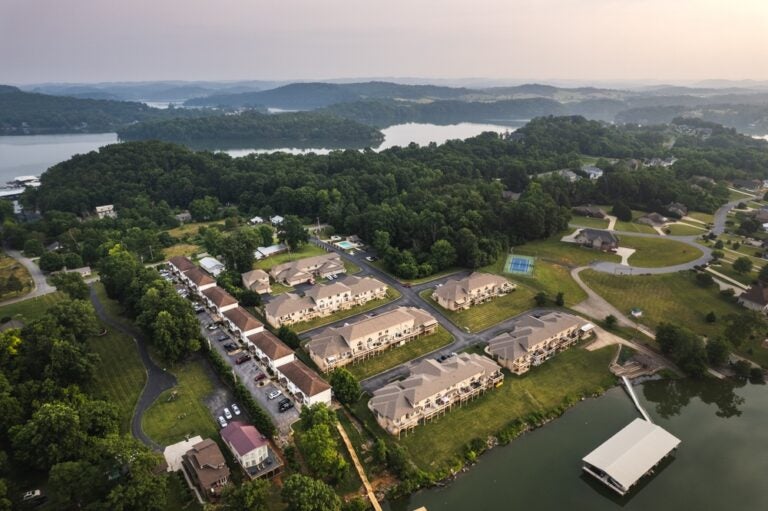 Aerial view of a lakeside residential complex at Boone Lake, with docks, parking lots, and forested hills around the water.
