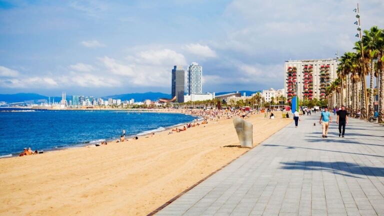 Sandy Barceloneta beach stretching along the Mediterranean, with Barcelona’s waterfront buildings lining the shore.