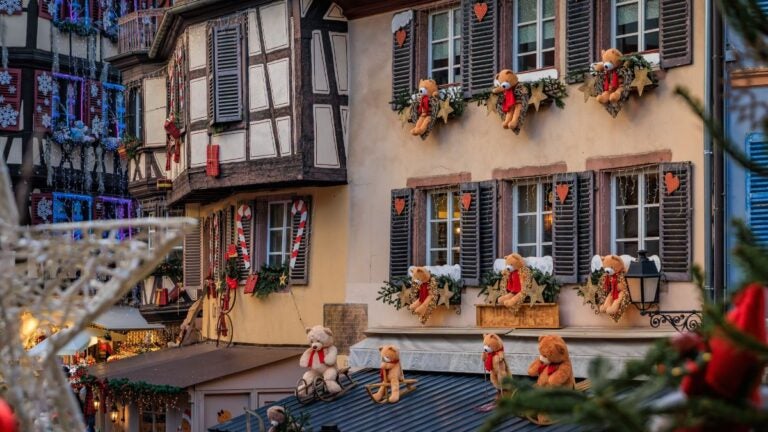 Half timbered houses decorated with teddy bears and red and gold ornaments at the Colmar Christmas market