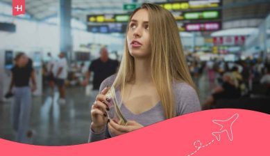 A traveler holding currency at an airport terminal, preparing for the cost of living in Poland.
