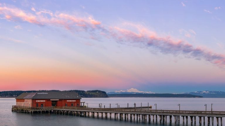 Historic wooden pier and wharf building stretching out over calm water in Coupeville on Whidbey Island, Washington