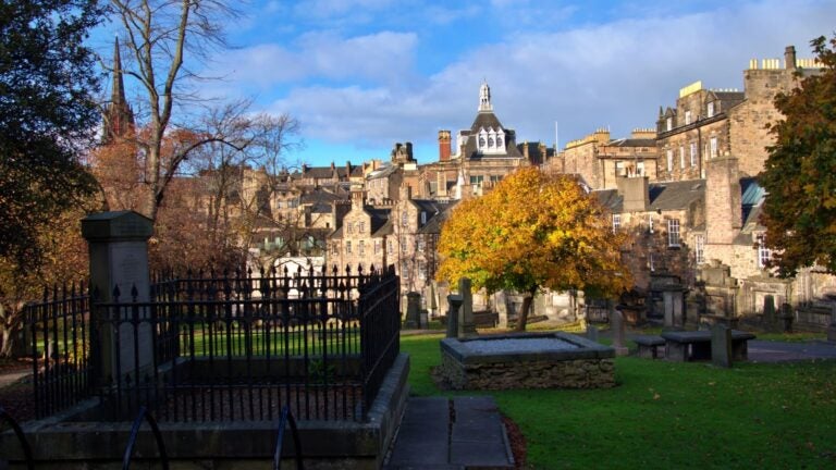 Gravestones in Greyfriars Kirkyard with Edinburgh’s Old Town behind in late autumn