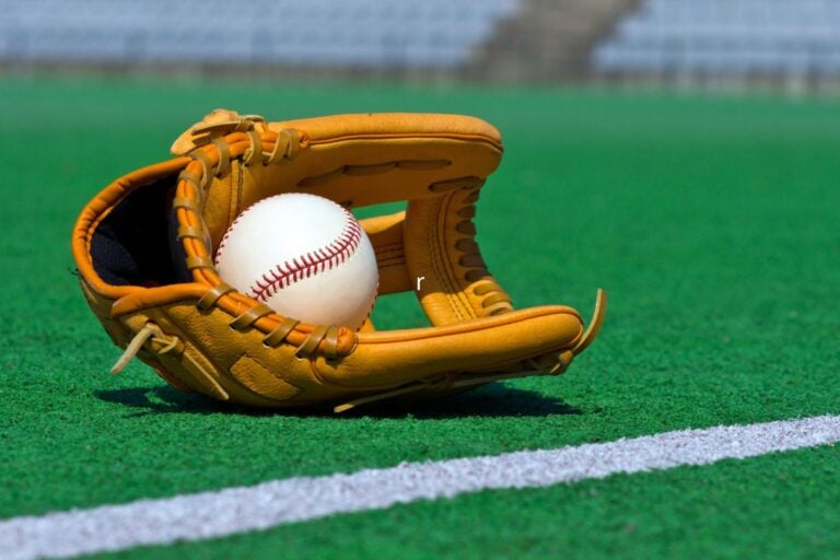 Baseball glove and ball laying in the green stadium field.