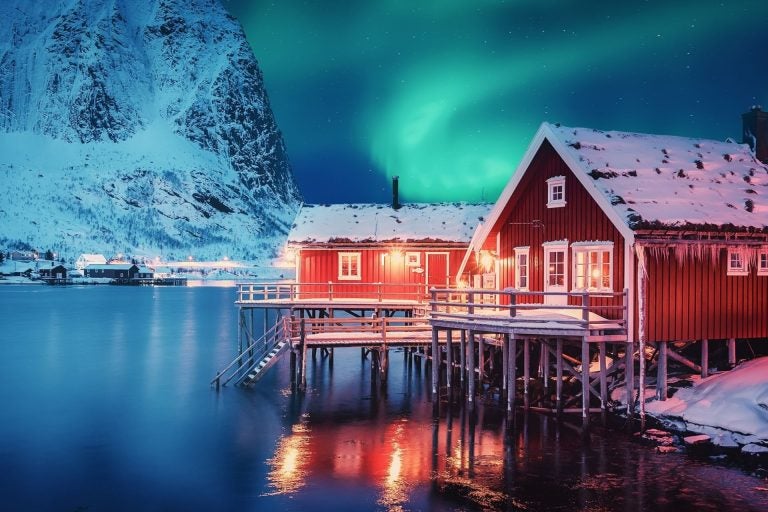 Scenic photo of winter fishing village with northern lights